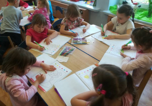 Dzieci przy stolikach kolorują bukiet wg podanego kodu.